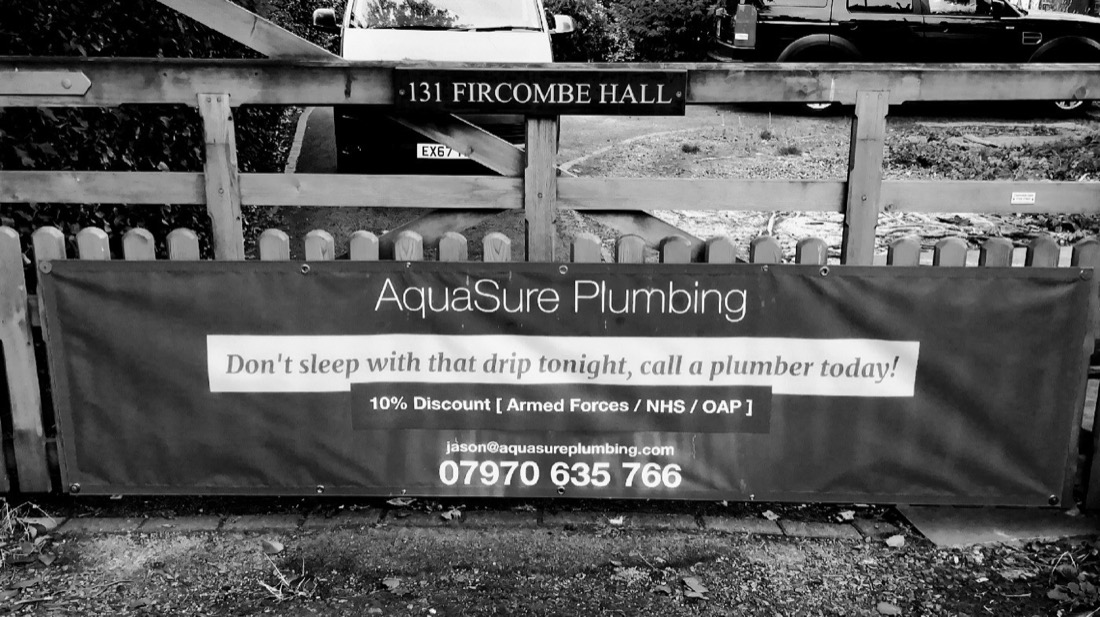 AquaSure Plumbing banner on a fence: don't sleep with that drip tonight, call a plumber today