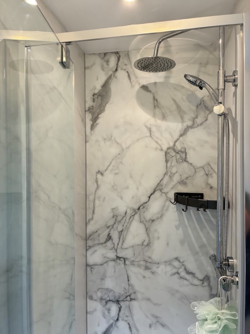 Walk-in shower with rainfall head and marble-effect panels