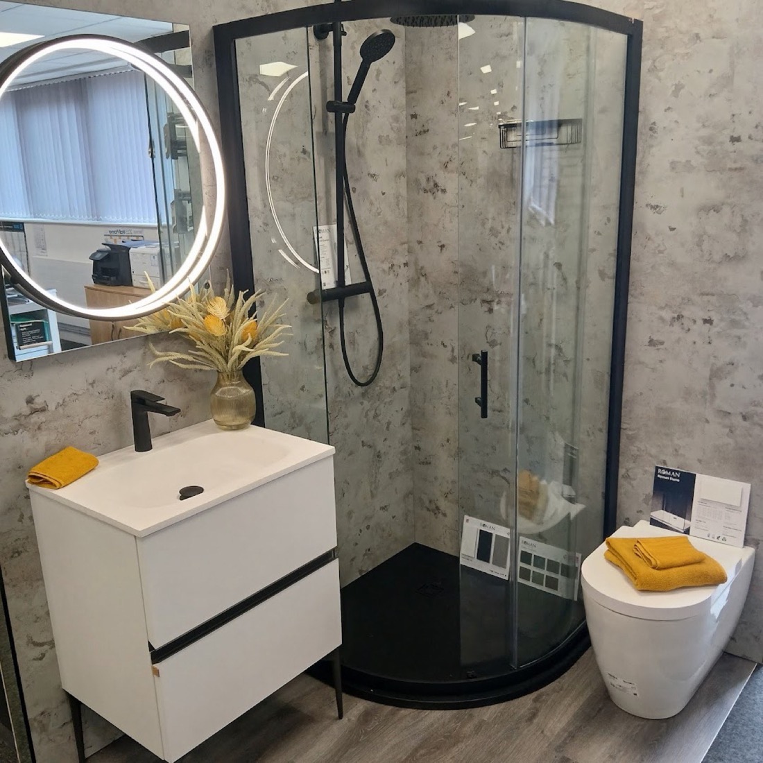 Bathroom with round LED mirror, black quadrant shower and concrete-effect walls